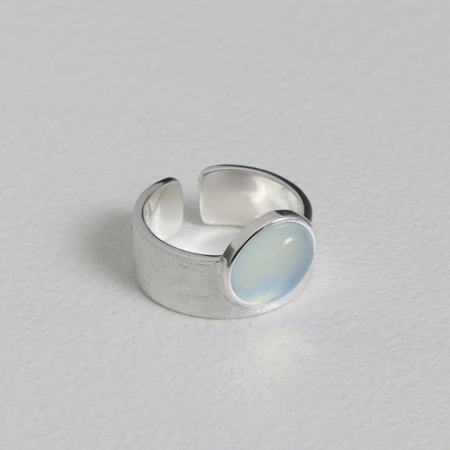 Silver ring with a light blue stone on a gray background