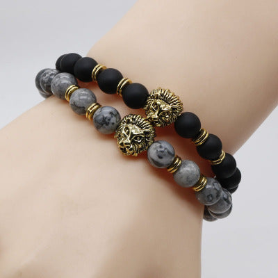 Two beaded bracelets with lion head charms on a wrist against a light background