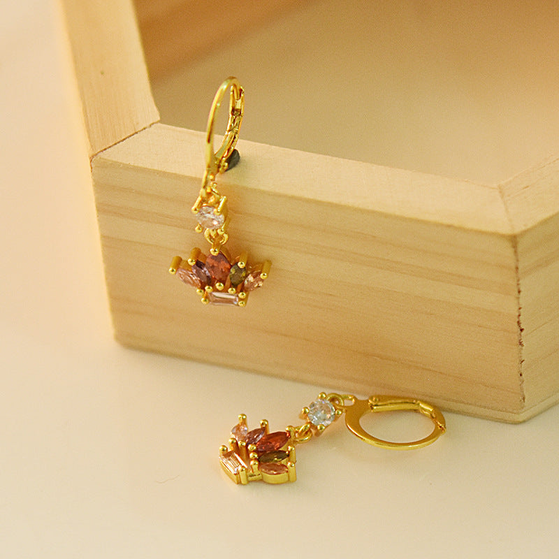 Gold earrings with gemstones on a wooden box
