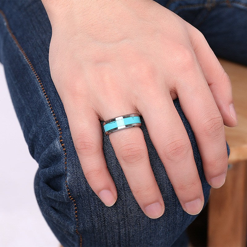 Hand wearing a turquoise ring on a denim background