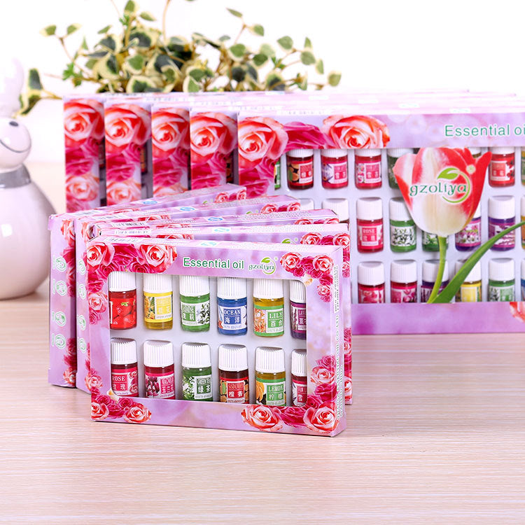 Set of essential oil bottles in a decorative box with floral design on a wooden surface.