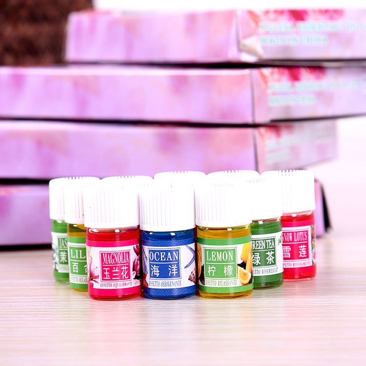 Row of small bottles with colorful labels on a wooden surface, with a blurred pink and white striped background.