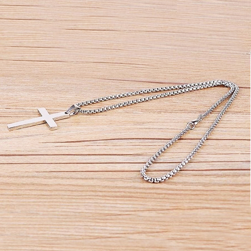 Silver cross pendant necklace on a wooden surface