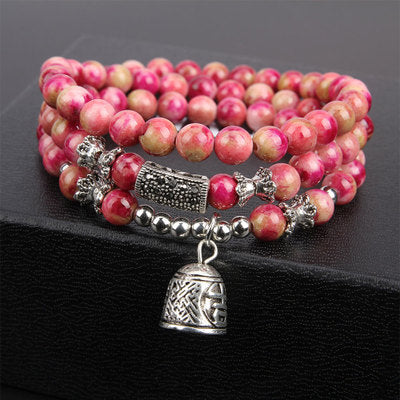 Pink beaded bracelet with silver charms on a black background