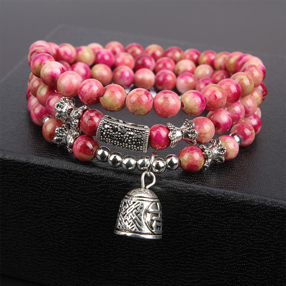 Pink beaded bracelet with silver charms on a black background