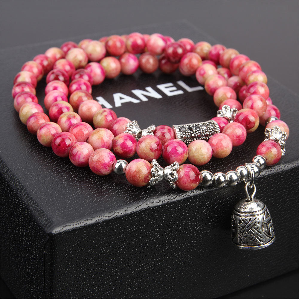 Pink beaded bracelet with silver charms on a Chanel box