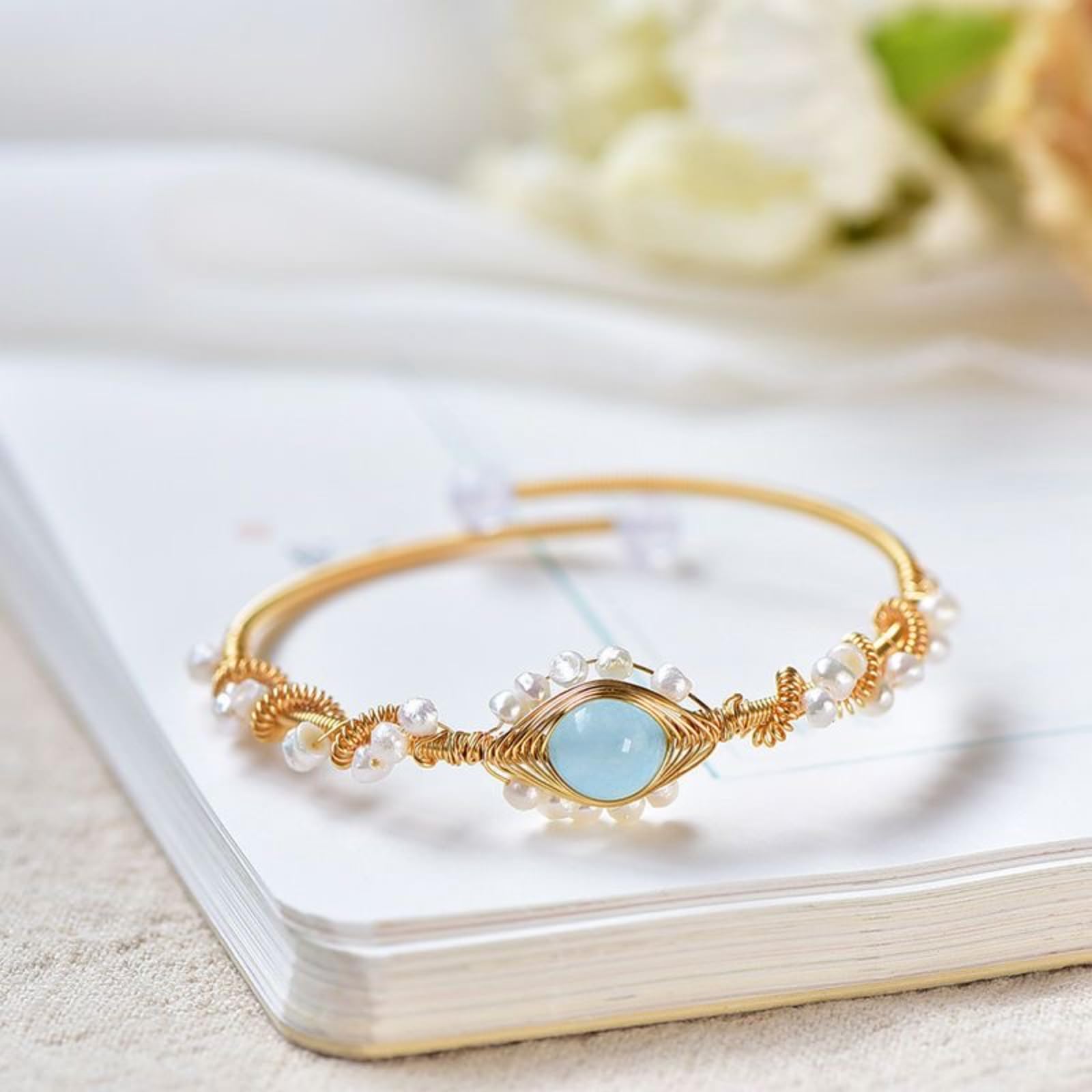 Gold bracelet with a blue gemstone on a white surface