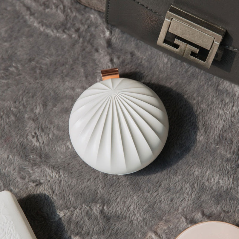 Round white decorative item on a textured surface with a metallic object in the background
