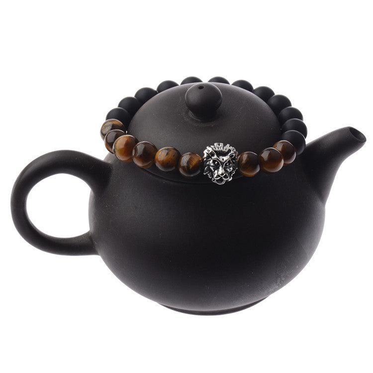 Black teapot with a beaded bracelet on the lid against a white background