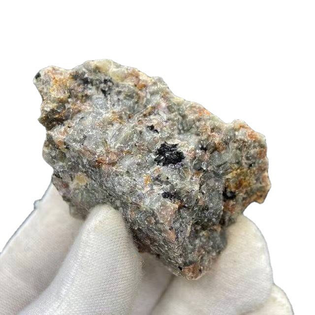 Mineral sample held by a white gloved hand on a white background