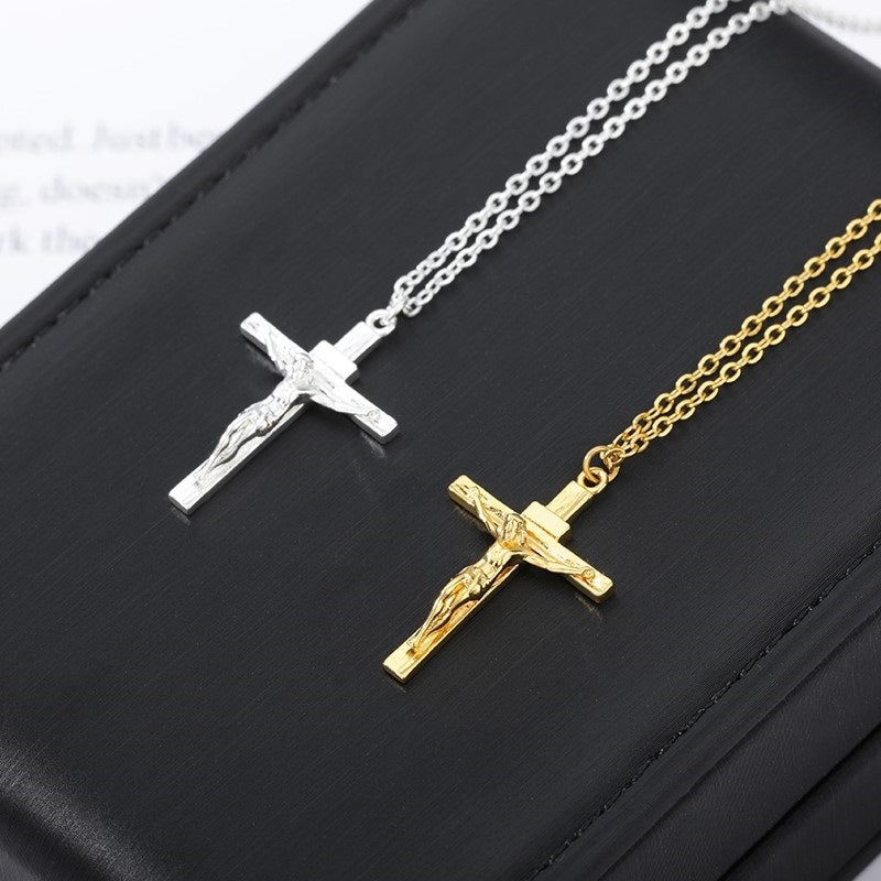 Two crucifix pendants, one gold and one silver, on a black surface.