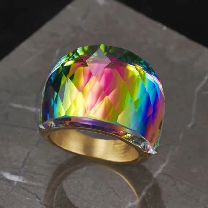 Multicolored crystal ring with gold band on a dark stone surface