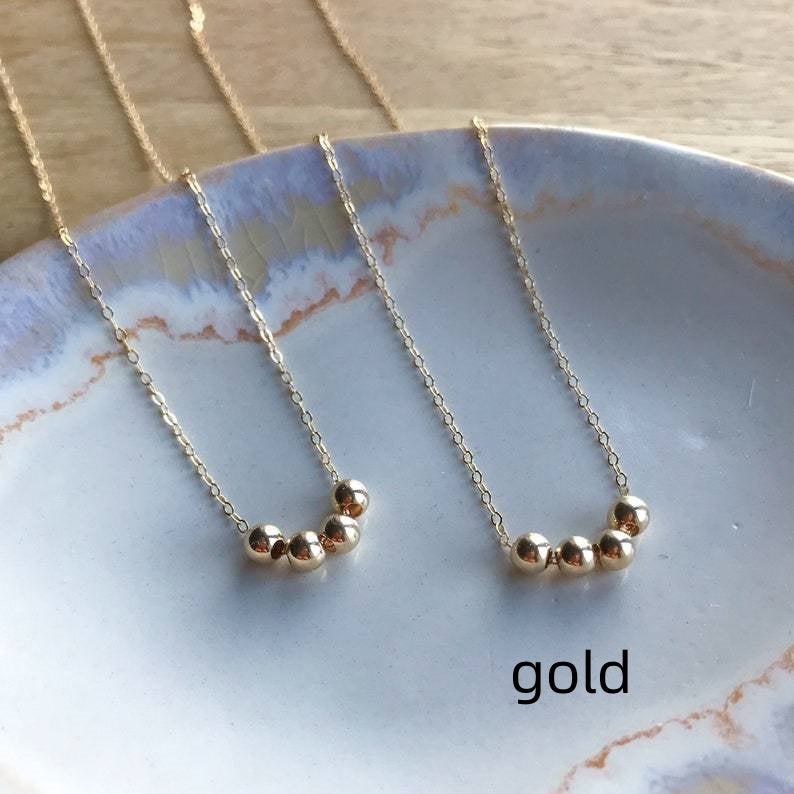 Gold necklace with small beads on a ceramic plate