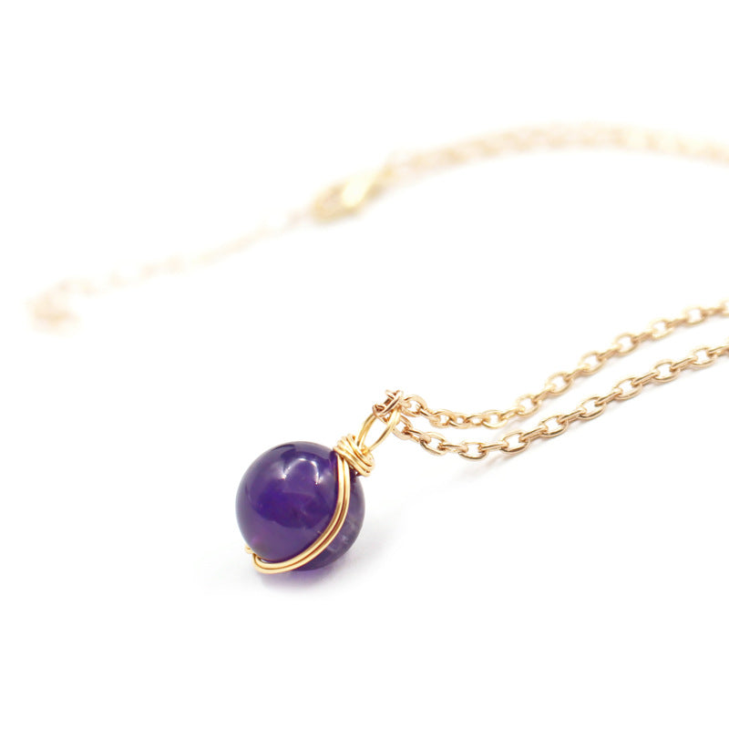 Gold necklace with a purple pendant on a white background