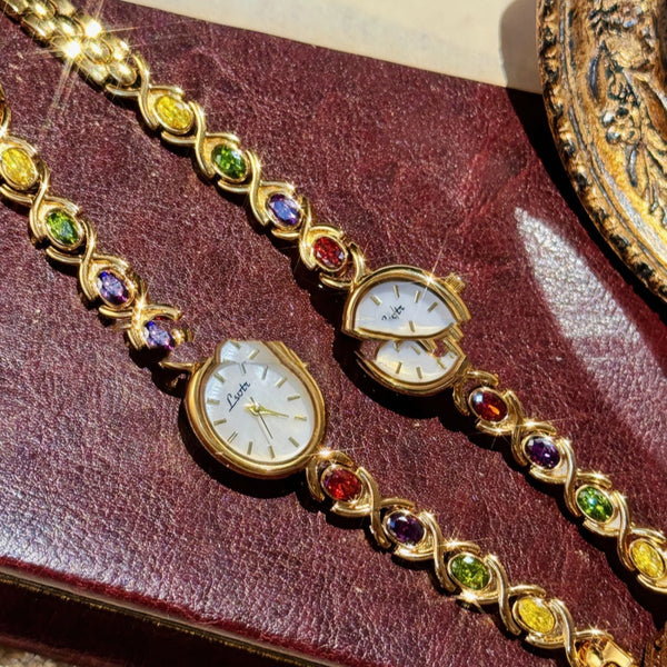 Gold bracelet with gemstones on a red leather surface