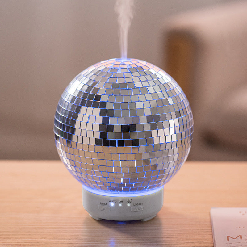 Silver disco ball humidifier on a wooden surface with a blurred background