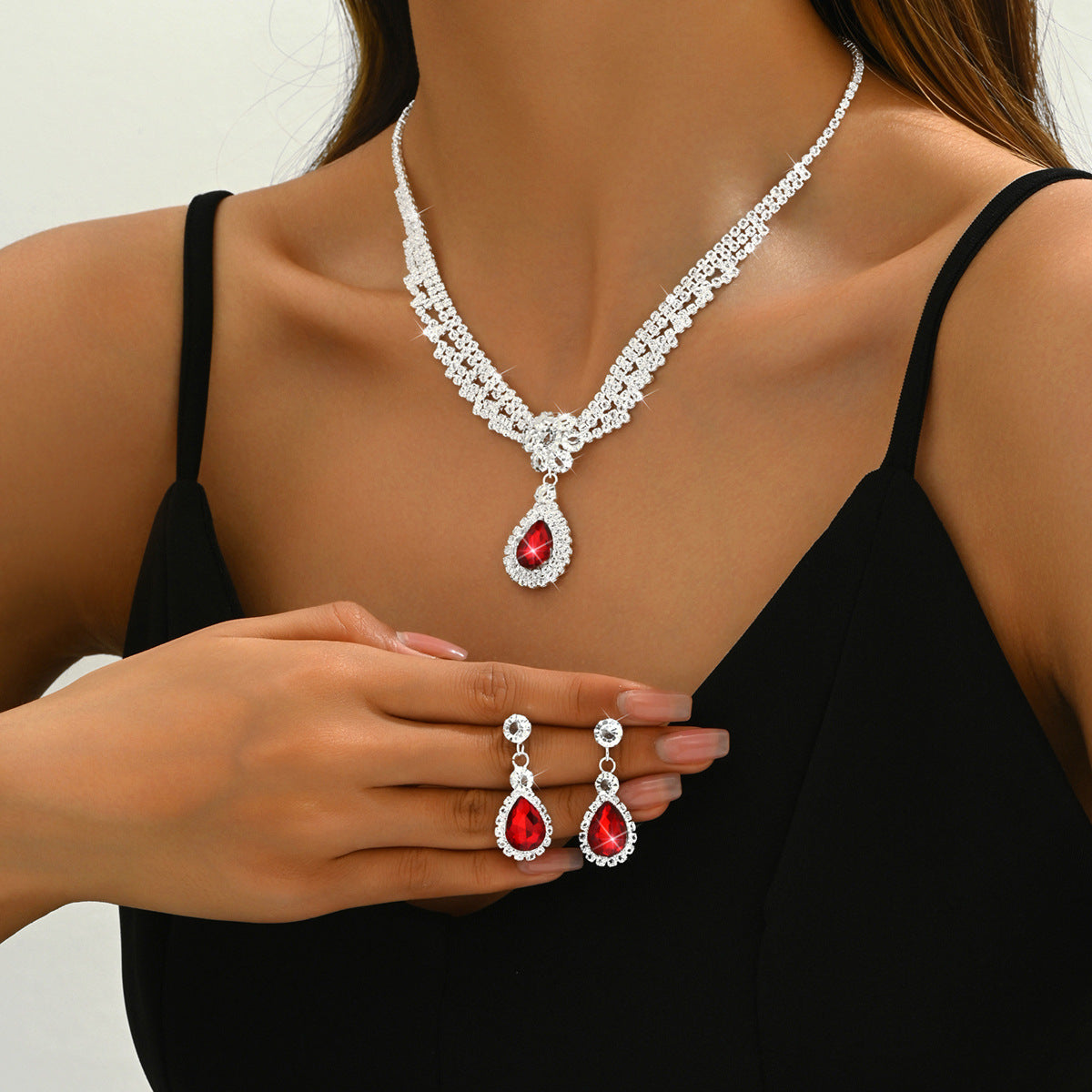 Jewelry set with necklace and earrings featuring red gemstones on a model.