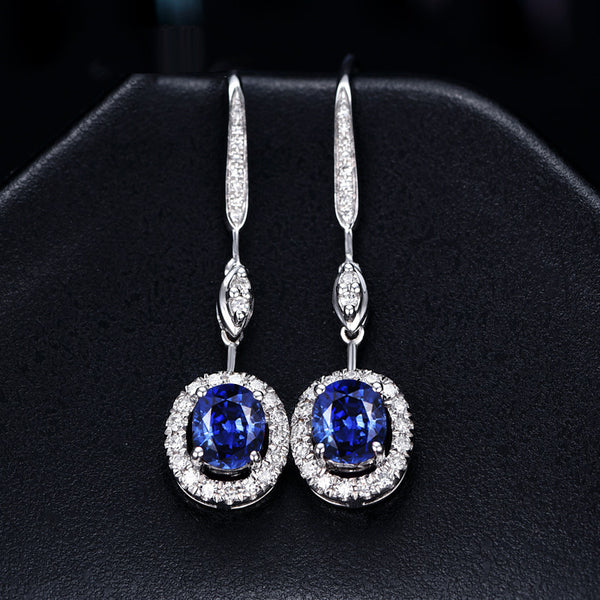 Pair of earrings with blue gemstones and diamond accents on a dark background