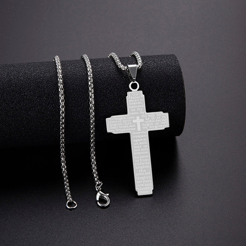 Silver cross pendant necklace on a black cylindrical stand with a dark background