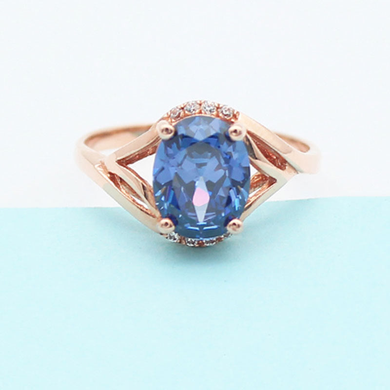Rose gold ring with a blue gemstone on a light blue background
