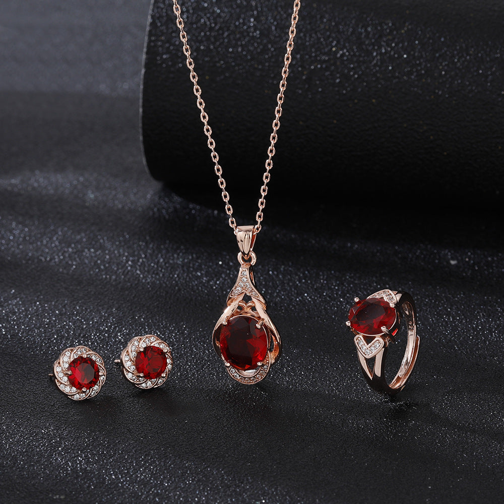 Jewelry set with necklace, earrings, and ring featuring red gemstones on a dark background