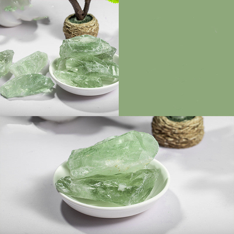 Green crystals in a white bowl on a light gray surface with a green color swatch.
