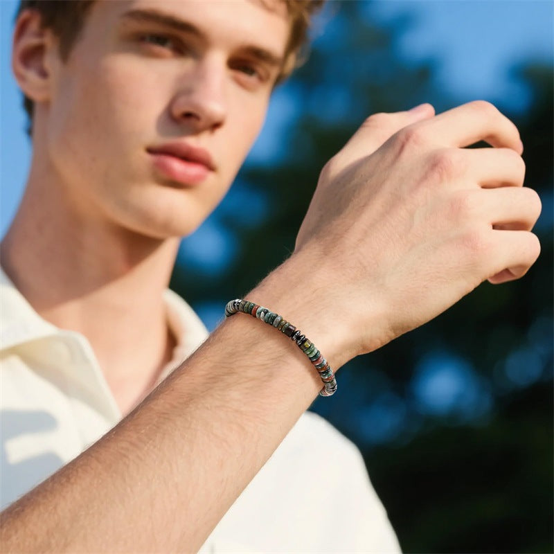 Man wearing a beaded bracelet with a blurred outdoor background