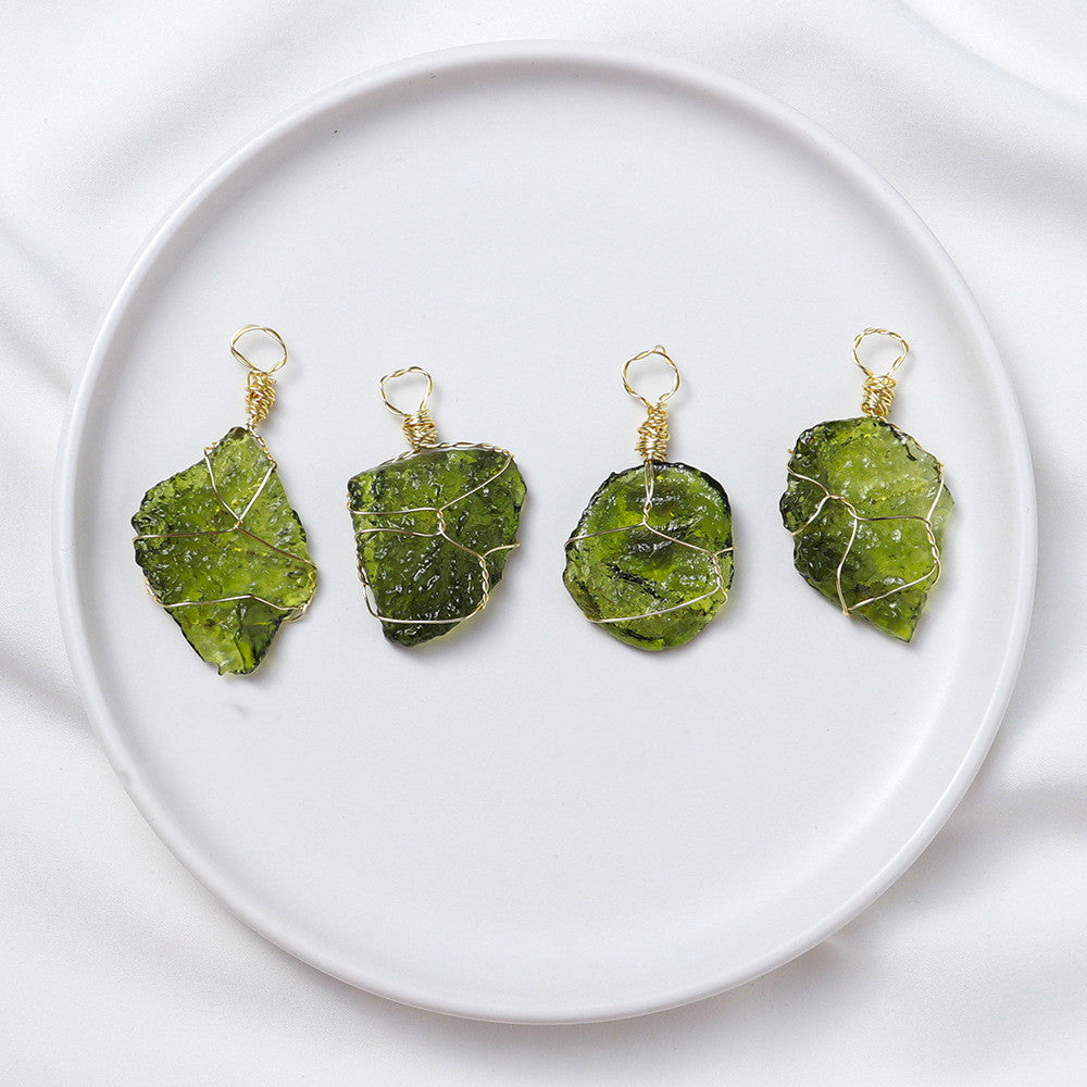 Four green stone pendants on gold wires displayed on a white plate.