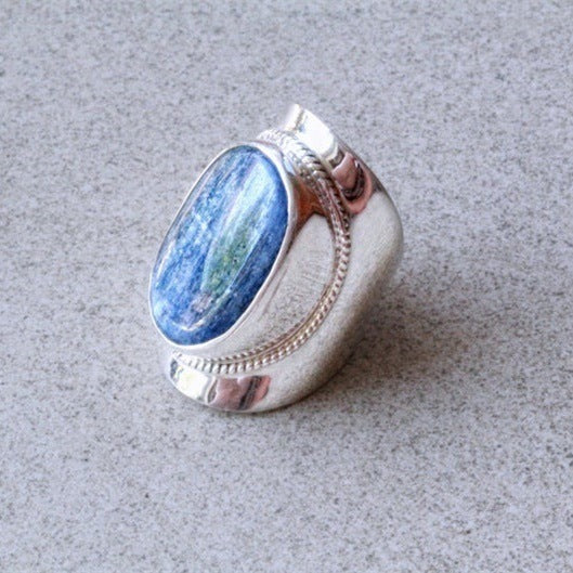 Silver ring with a blue stone on a gray surface
