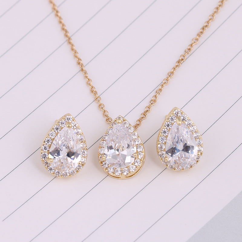 Gold necklace with teardrop-shaped crystal pendants on a light background