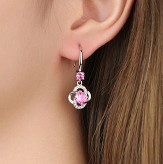 Close-up of a person wearing pink flower-shaped earrings.