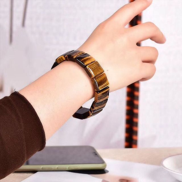 Hand wearing a wooden bracelet with a blurred background