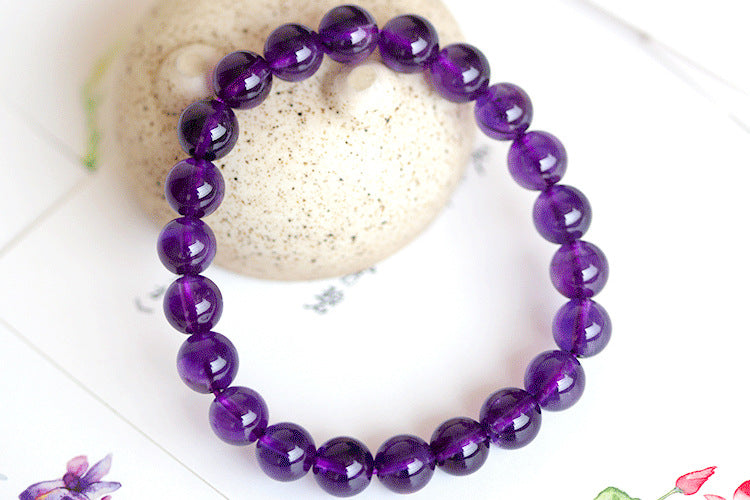 Purple beaded bracelet on a white surface with a blurred background