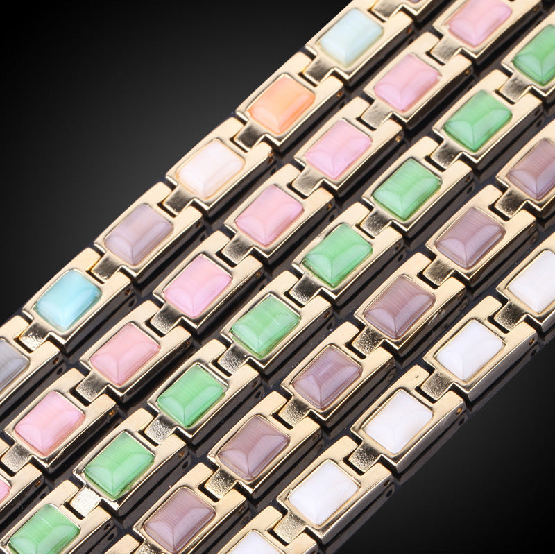 Bracelet with gold links and multicolored gemstones on a dark background