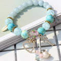 Bracelet with blue and gold beads and charms on a light surface
