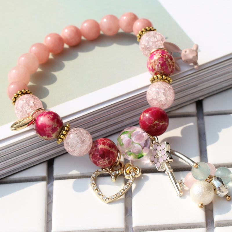 Beaded bracelet with pink and red beads and charms on a light surface