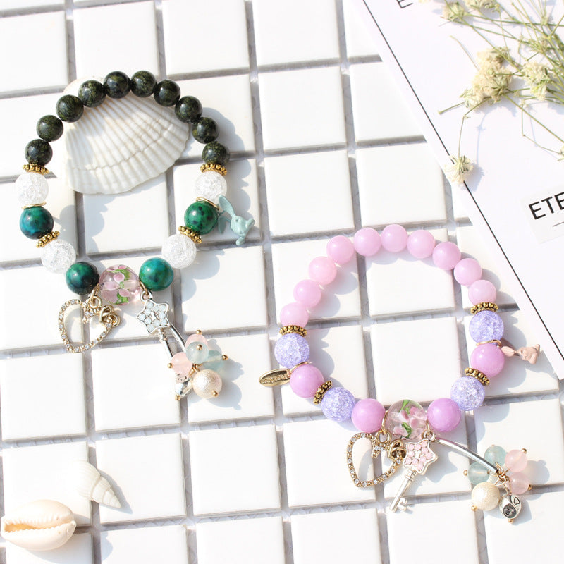 Two beaded bracelets with charms on a grid background