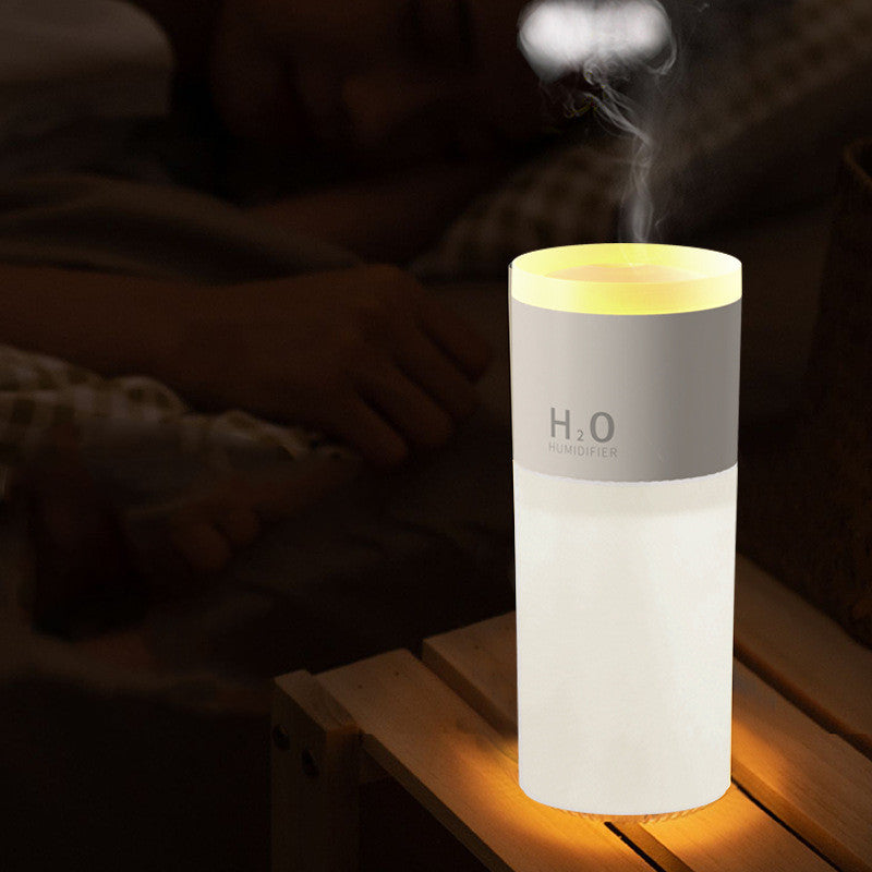 H2O humidifier emitting mist on a wooden surface with a dark background