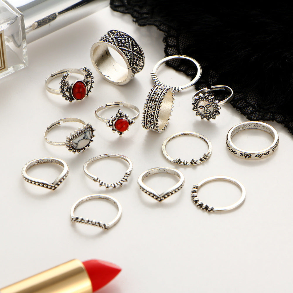 Collection of silver rings with various designs on a white surface with a red lipstick.
