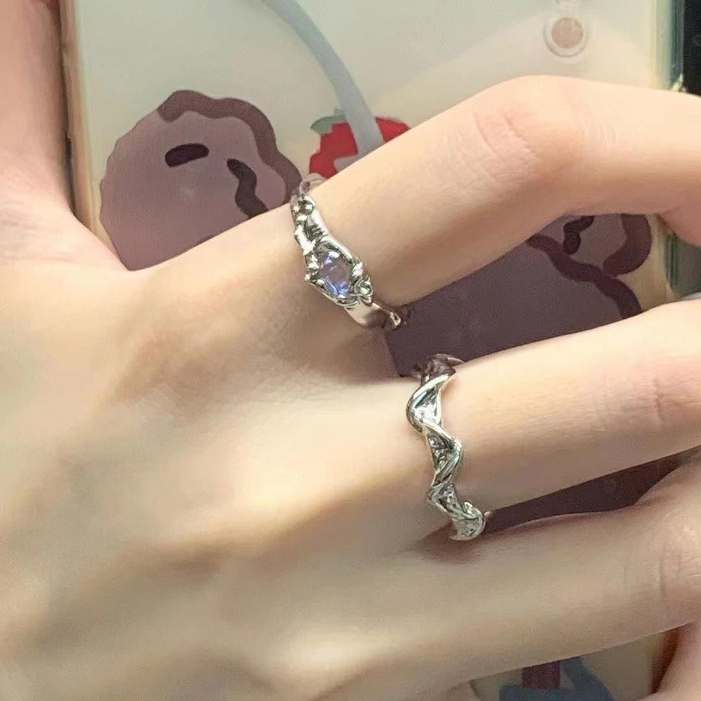 Close-up of a hand wearing two silver rings with a blurred background