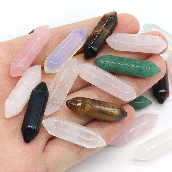 Hand holding a collection of multicolored crystals on a white background