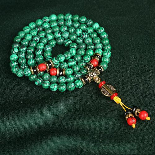 Green beaded necklace with red and gold accents on a dark green background