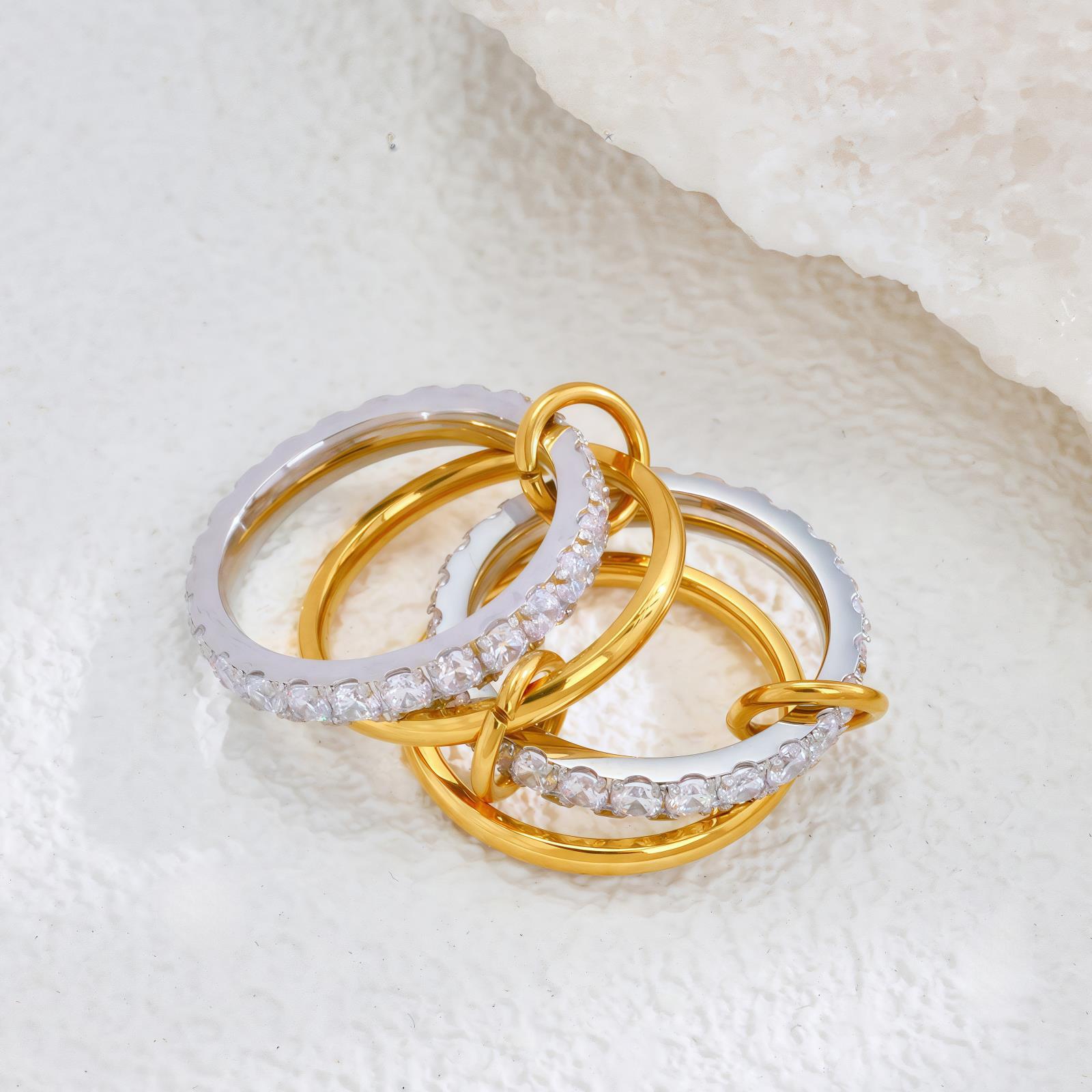 Three gold and silver rings with diamond accents on a textured white surface