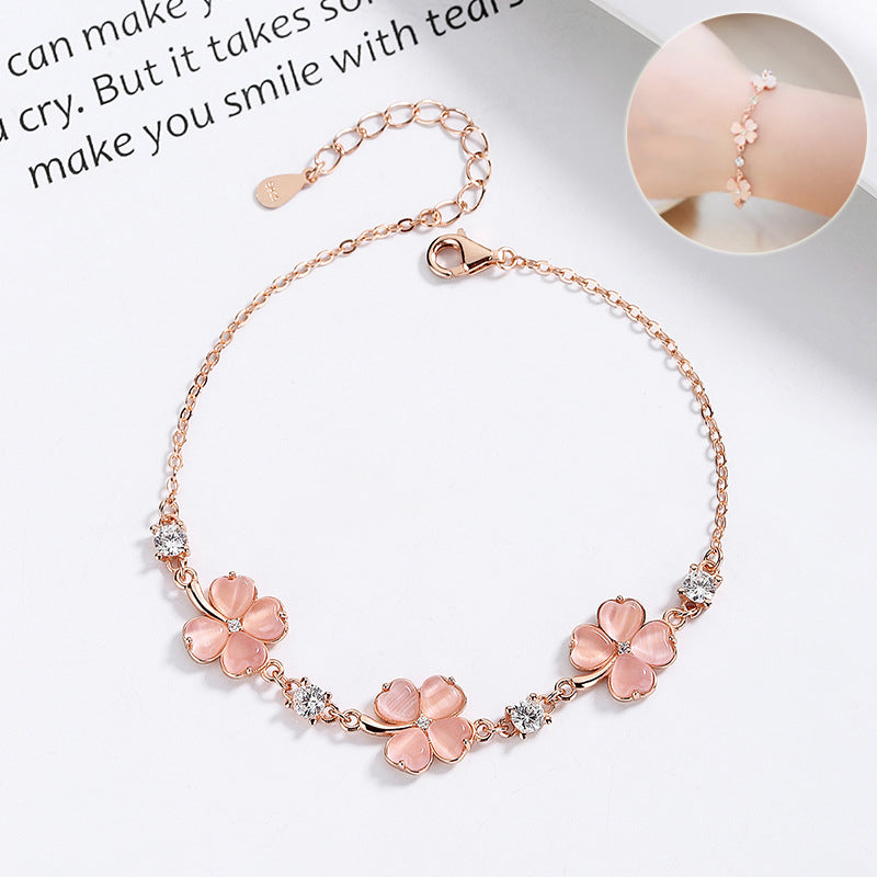 Rose gold bracelet with pink floral charms on a white background