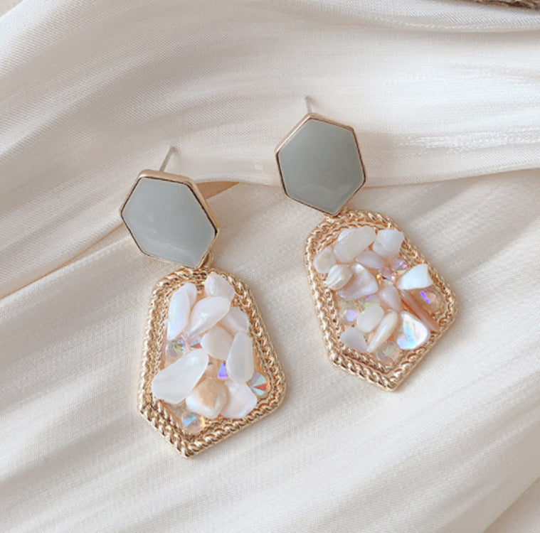 Gold and white earrings on a beige fabric background