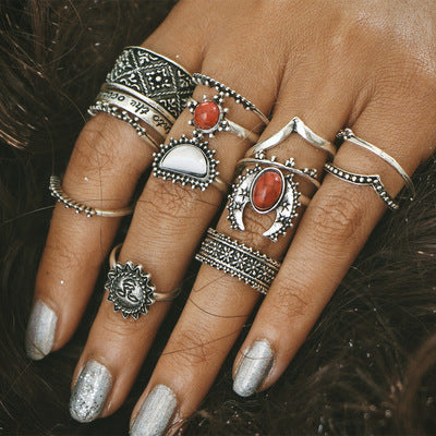 Close-up of a hand wearing multiple silver rings with gemstones on a dark background