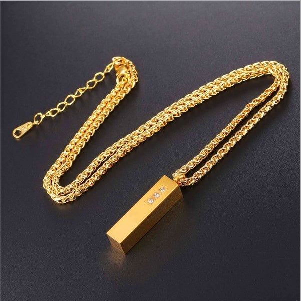 Gold necklace with a rectangular pendant on a dark background
