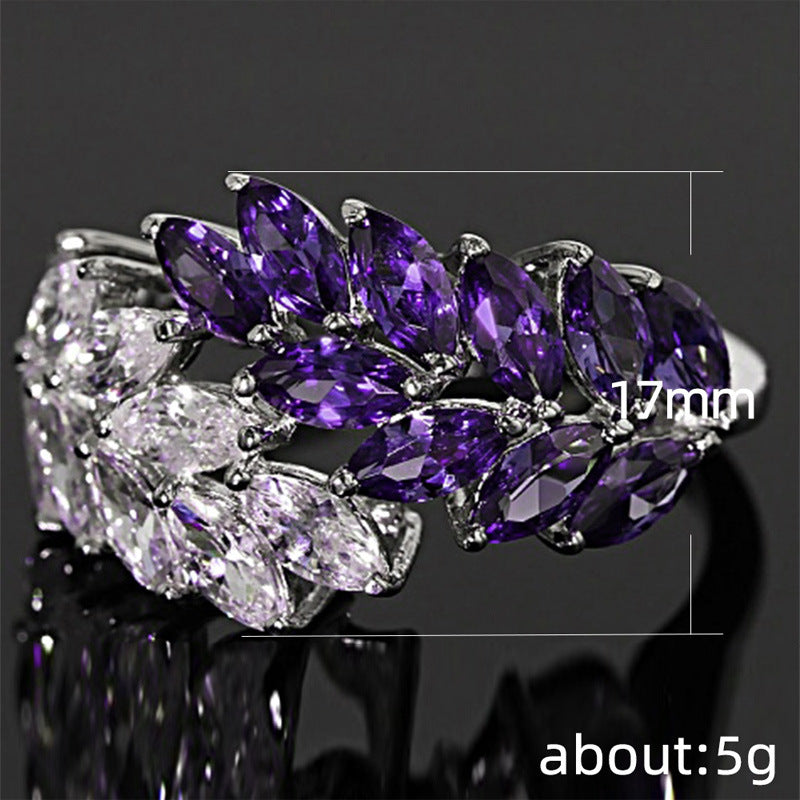Ring with purple and clear gemstones on a reflective surface