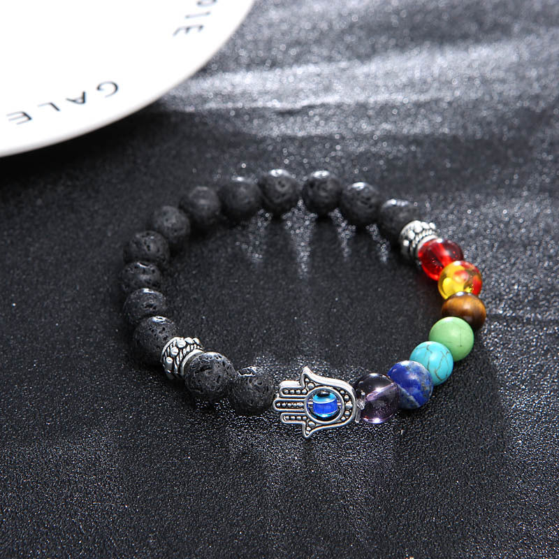 Multicolored beaded bracelet with Hamsa hand charm on a dark surface