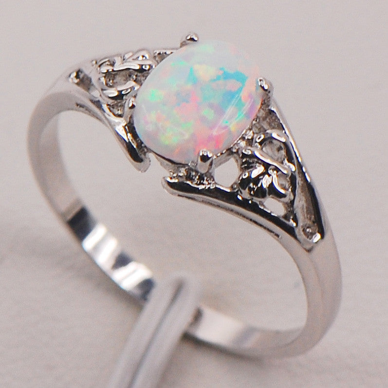 Silver ring with a colorful opal stone on a light gray background